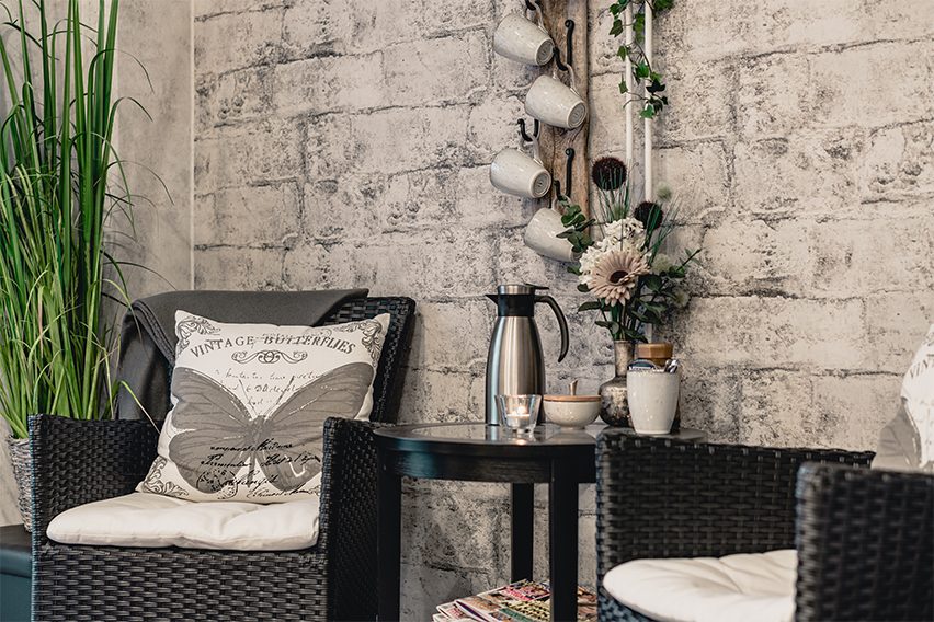 Sittplatsen med kaffetermos, koppar på vägghängare och en grön växt