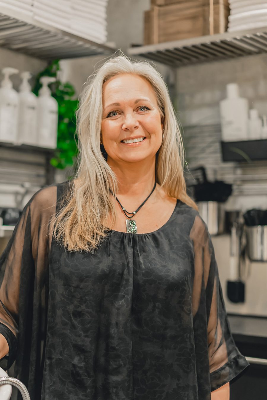 Susanne Wiklöf står i salongen framför hyllorna med hårprodukter